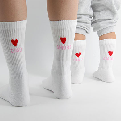 Partnerlook Socken in weiß und von hinten mit  2 roten Herzen, Aufschrift rosa "Ciao Amore". Ciao links, Amore rechts.