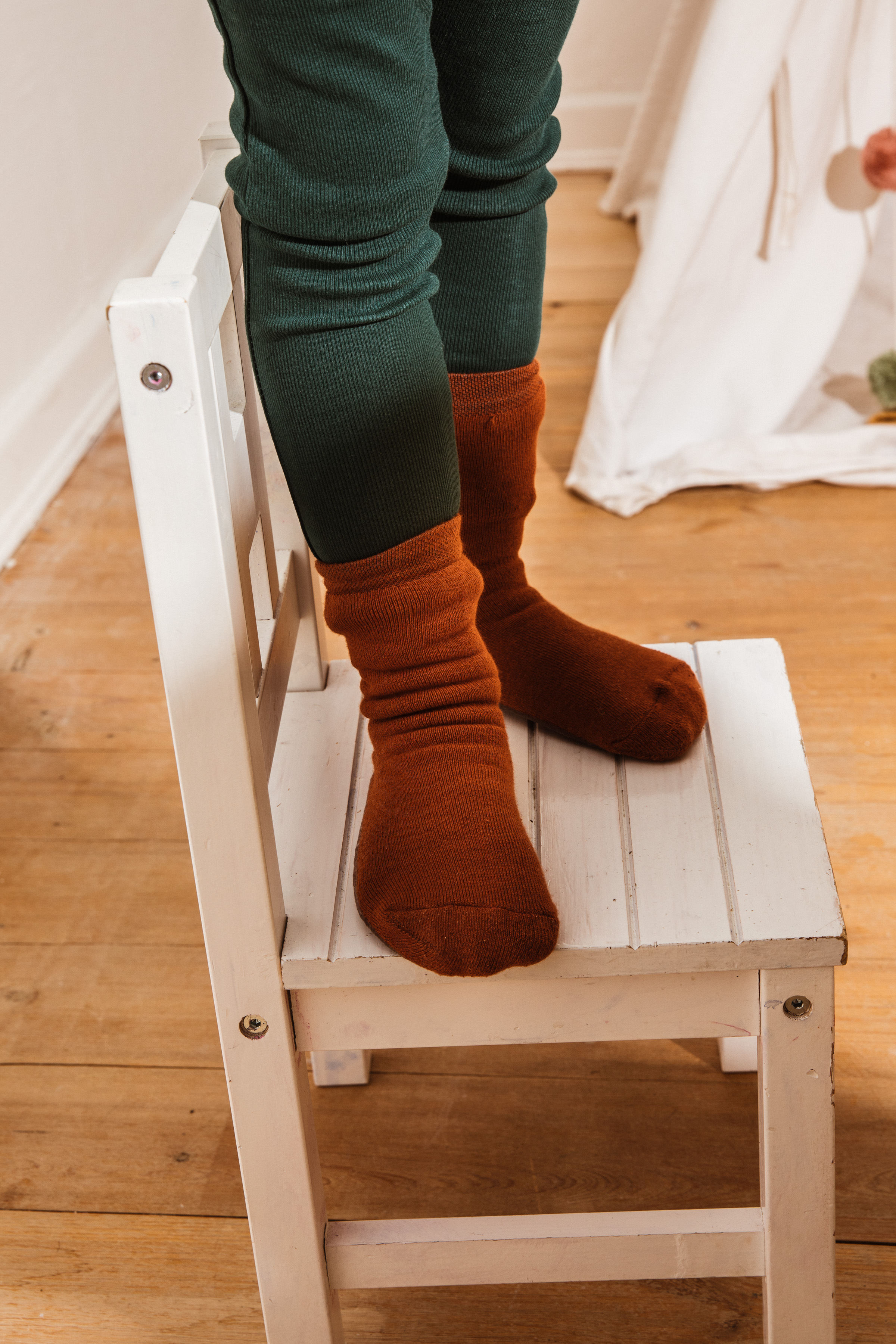 Junge auf Stuhl stehend mit Stoppersocken SoftStep in Kupfer