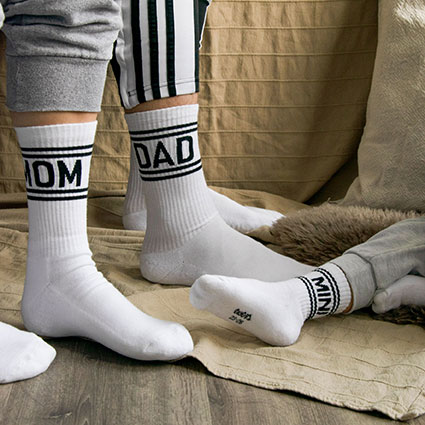 Mom, Dad und Mini Tennissocken in Weiß mit schwarzem Schriftzug und Ringel. Von Frau-, Mann- und Kinderfüßen präsentiert