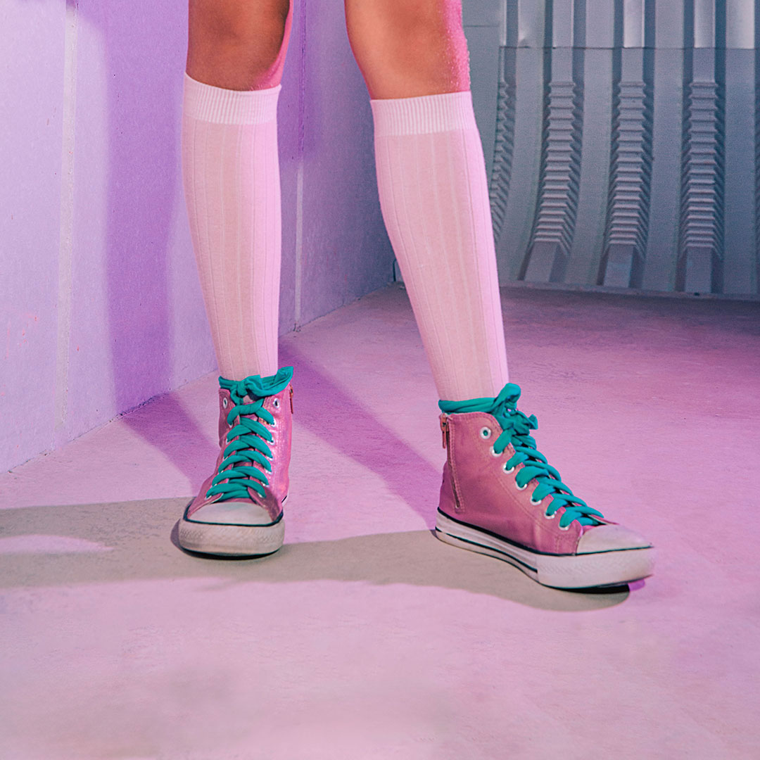 Kinderbeine mit weißen Kniestrümpfen und Converse Schuhen in Pink & Lapis.