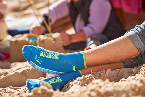 Familie am Strand mit Beachies, der Strand- und Wassersportsocke in Blau.