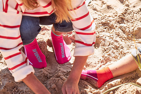 Frau mit Kind im Sand-Strand hockend mit den Beachies in Pink und Blockringel