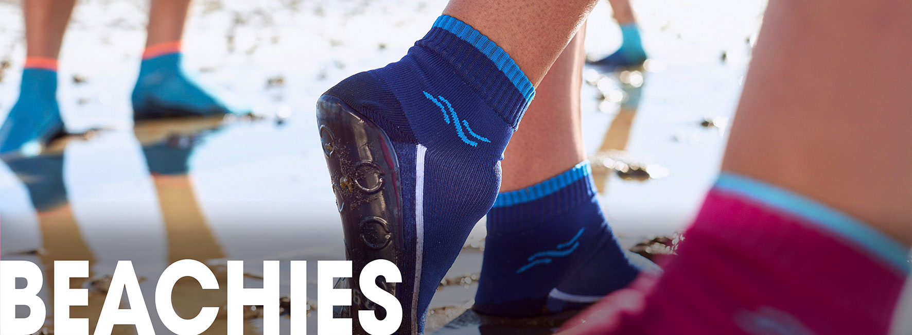 Meereswatt mit Jungen- und Mädchen Beinen und den BEACHIES, den Strand- und Wassersportsocken in Blau, Pink und Lapis.