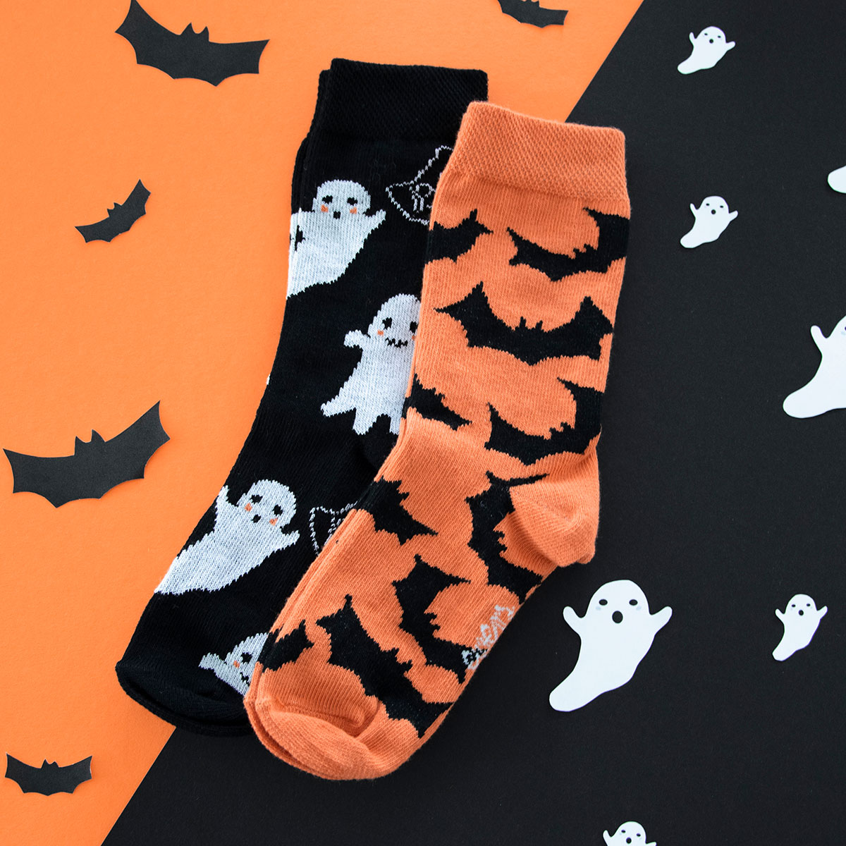Halloween Herbst Socken mit Motiv Geist/Gespenst in weiß auf schwarz sowie Fledermäusen in schwarz auf orange vor dem Hintergrund mit Fledermäusen und Geistern/Gespenstern auf orange und schwarz.